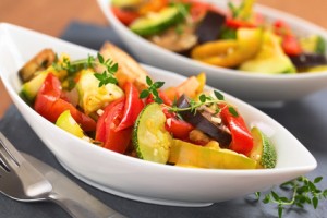 Two bowls of fresh homemade Ratatouille made of eggplant, zucchini, bell pepper and tomato and seasoned with herbs (garlic, thyme, oregano) (Selective Focus, Focus on the front leaves of the thyme sprig on the meal)