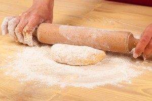 Working on unfinished dough with a rolling pin