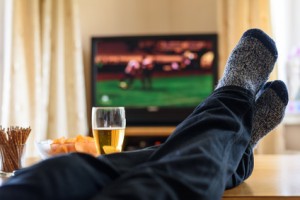 Television, TV watching (football match) with feet on table and huge amounts of snacks - stock photo
