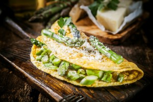 Close up Gourmet Appetizing Egg Omelette Main Dish, Garnished with Cheese and Asparagus on Top of Wooden Serving Board