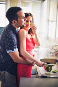 Young couple cooking together in the kitchen while man embracing his pregnant wife