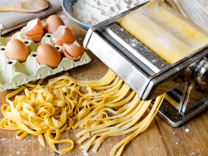 Fresh pasta cutting in machine. Fettuccini homemade.