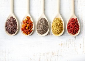 Wooden spoons of various superfoods on white wooden background