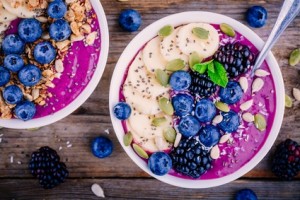 Purple smoothie bowl with fresh blackberries, blueberries, banana, sunflower seeds, pumpkin seeds, chia  seeds and coconut